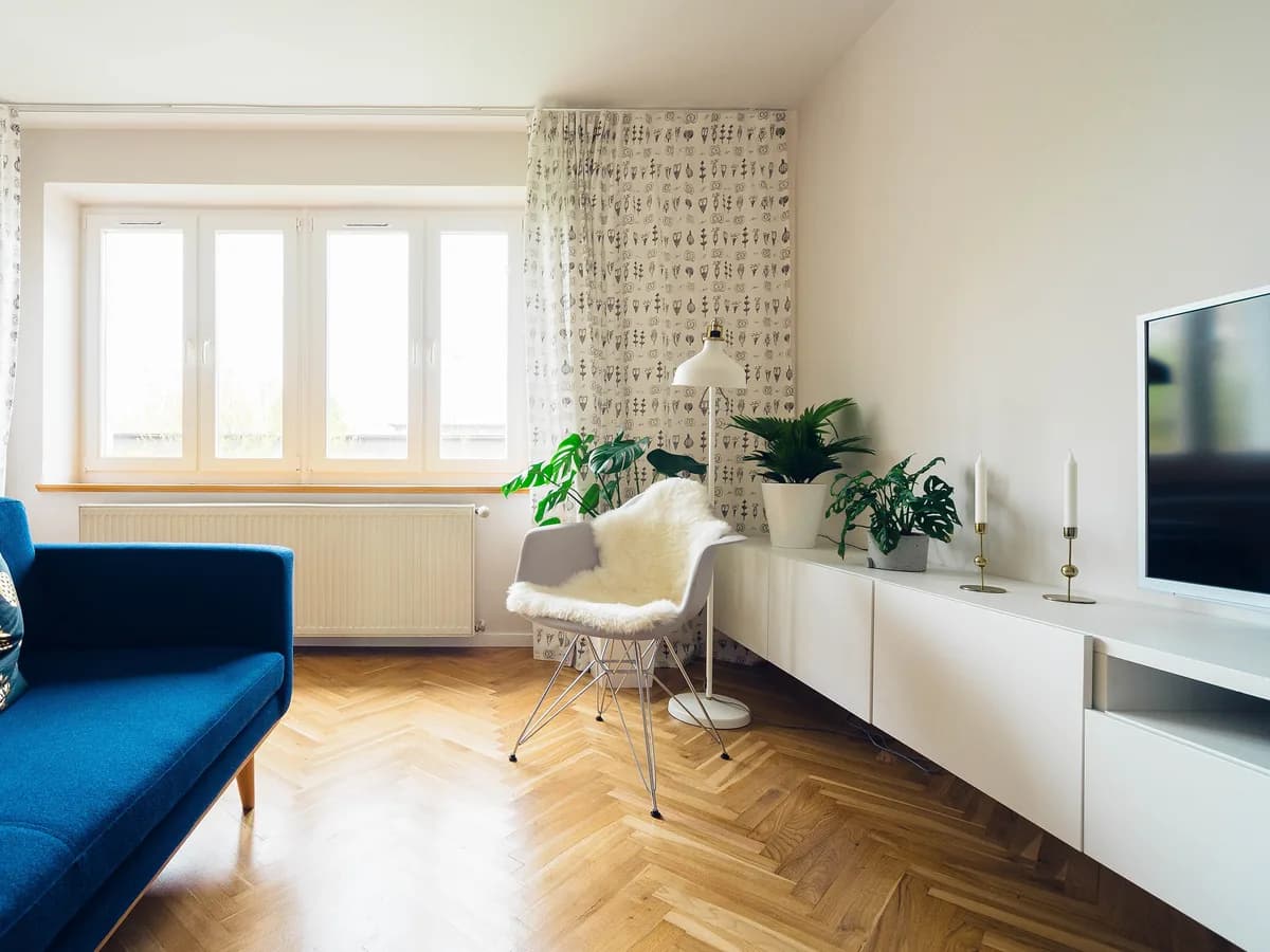Ruang keluarga terang dengan sofa biru dan lantai kayu